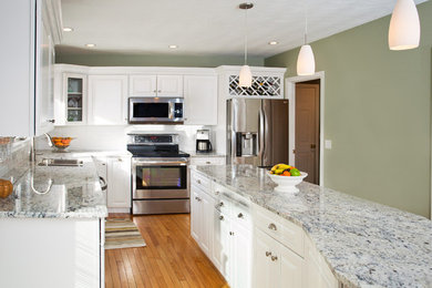 Inspiration for a mid-sized modern l-shaped light wood floor eat-in kitchen remodel in Boston with a double-bowl sink, raised-panel cabinets, white cabinets, granite countertops, white backsplash, subway tile backsplash, stainless steel appliances and an island