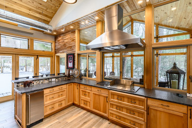 Inspiration for a large rustic u-shaped light wood floor and brown floor eat-in kitchen remodel in Philadelphia with a farmhouse sink, recessed-panel cabinets, medium tone wood cabinets, granite countertops, brown backsplash, wood backsplash, stainless steel appliances, a peninsula and black countertops