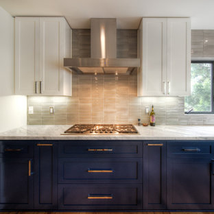 Inspiration pour une grand cuisine américaine design en U avec un évier de ferme, un placard à porte shaker, des portes de placard blanches, une crédence beige, une crédence en carreau de porcelaine, un électroménager en acier inoxydable, un sol en bois clair, un îlot central, un sol jaune et un plan de travail blanc.