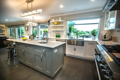 Inspiration for a mid-sized transitional l-shaped dark wood floor and brown floor eat-in kitchen remodel in San Francisco with a farmhouse sink, shaker cabinets, white cabinets, gray backsplash, stone tile backsplash, stainless steel appliances and an island
