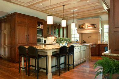 Example of a large transitional u-shaped dark wood floor open concept kitchen design in Denver with raised-panel cabinets, dark wood cabinets, granite countertops, beige backsplash, stone tile backsplash, stainless steel appliances and an island