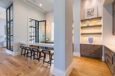 Idées déco pour une cuisine ouverte contemporaine en L et bois brun de taille moyenne avec un placard avec porte à panneau encastré, un plan de travail en quartz modifié, une crédence beige, une crédence en carrelage de pierre, parquet clair, une péninsule, un sol beige et un plan de travail blanc.