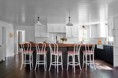 Inspiration for a large cottage l-shaped dark wood floor and brown floor eat-in kitchen remodel in New York with a farmhouse sink, shaker cabinets, black cabinets, soapstone countertops, white backsplash, ceramic backsplash, paneled appliances and an island