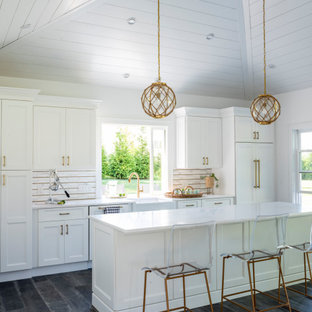 Coastal open concept kitchen ideas - Open concept kitchen - coastal single-wall dark wood floor, black floor, shiplap ceiling and vaulted ceiling open concept kitchen idea in New York with a farmhouse sink, shaker cabinets, white cabinets, quartz countertops, multicolored backsplash, paneled appliances, an island and white countertops