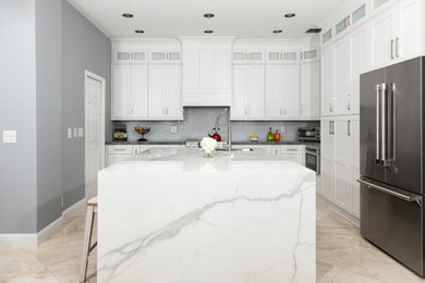 Inspiration for a transitional l-shaped beige floor kitchen remodel in Miami with an undermount sink, shaker cabinets, white cabinets, gray backsplash, stainless steel appliances, two islands and gray countertops