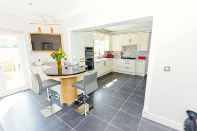 This is an example of a medium sized traditional l-shaped open plan kitchen in Other with a submerged sink, shaker cabinets, white cabinets, granite worktops, stainless steel appliances, vinyl flooring and a breakfast bar.