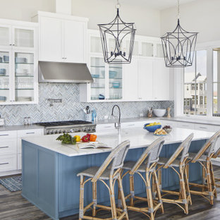 Expansive beach style l-shaped open plan kitchen in Other with an undermount sink, shaker cabinets, white cabinets, quartz benchtops, stainless steel appliances, vinyl floors, with island, brown floor, grey splashback, mosaic tile splashback and grey benchtop.