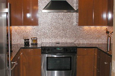 Bild på ett mellanstort funkis u-kök, med en undermonterad diskho, släta luckor, skåp i mellenmörkt trä, granitbänkskiva, orange stänkskydd och rostfria vitvaror