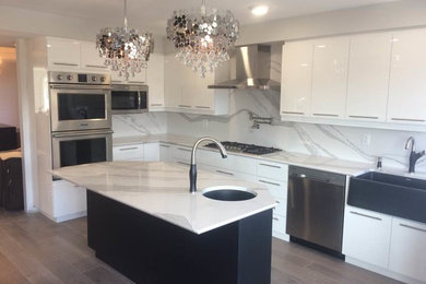 Mid-sized minimalist u-shaped eat-in kitchen photo in Toronto with a farmhouse sink, flat-panel cabinets, white cabinets, quartz countertops, white backsplash, stone slab backsplash, stainless steel appliances, an island and white countertops