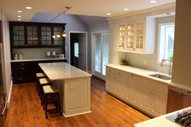Mid-sized transitional u-shaped medium tone wood floor and brown floor enclosed kitchen photo in Philadelphia with an undermount sink, raised-panel cabinets, white cabinets, marble countertops, white backsplash, window backsplash, stainless steel appliances and an island