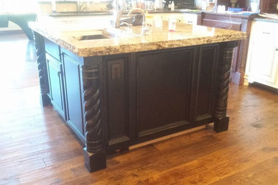 Kitchen - mid-sized traditional l-shaped medium tone wood floor kitchen idea in Oklahoma City with recessed-panel cabinets, dark wood cabinets, granite countertops and an island