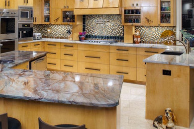 Example of a large trendy u-shaped ceramic tile enclosed kitchen design in Austin with an undermount sink, light wood cabinets, granite countertops, multicolored backsplash, stainless steel appliances, an island, flat-panel cabinets and glass tile backsplash