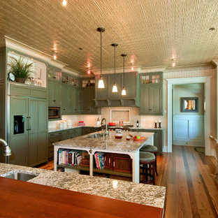 Imagen de cocina comedor en L, clásica, con armarios con paneles empotrados, puertas de armario verdes, electrodomésticos con paneles, fregadero de un seno y encimera de granito
