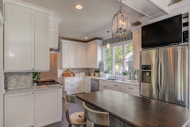 This is an example of a large classic galley kitchen/diner in Santa Barbara with a submerged sink, recessed-panel cabinets, white cabinets, quartz worktops, grey splashback, stone tiled splashback, stainless steel appliances, porcelain flooring, an island, brown floors and grey worktops.