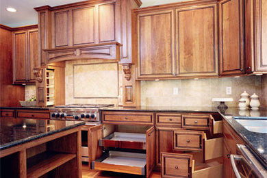 Exemple d'une cuisine américaine chic en bois brun avec un évier encastré, un placard avec porte à panneau encastré, un plan de travail en granite, un électroménager en acier inoxydable et îlot.