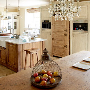 Idee per una cucina shabby-chic style di medie dimensioni con lavello stile country, ante con riquadro incassato, isola e pavimento beige