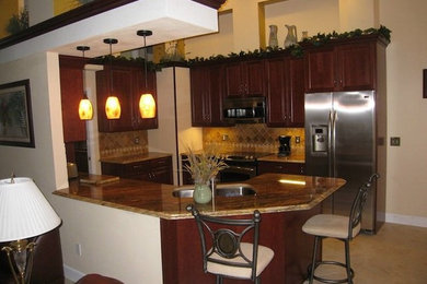 This is an example of a small traditional u-shaped open plan kitchen in Orlando with a double-bowl sink, raised-panel cabinets, dark wood cabinets, granite worktops, brown splashback, ceramic splashback, stainless steel appliances, cement flooring, a breakfast bar and beige floors.