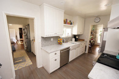 Enclosed kitchen - mid-sized transitional l-shaped vinyl floor and gray floor enclosed kitchen idea in San Diego with a farmhouse sink, raised-panel cabinets, white cabinets, quartzite countertops, gray backsplash, subway tile backsplash, stainless steel appliances and a peninsula