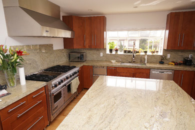 Example of a large trendy u-shaped light wood floor and beige floor enclosed kitchen design in San Diego with a single-bowl sink, shaker cabinets, medium tone wood cabinets, granite countertops, beige backsplash, stone slab backsplash, stainless steel appliances and an island