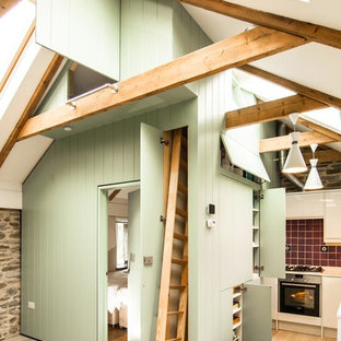 Small country l-shaped eat-in kitchen in London with flat-panel cabinets, green cabinets, light hardwood floors, red splashback and ceramic splashback.