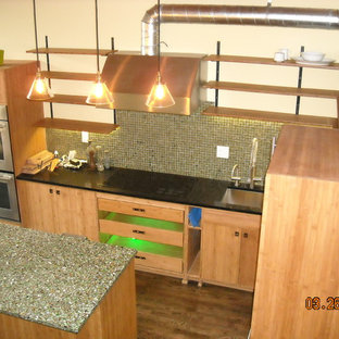 Design ideas for an industrial eat-in kitchen in Portland with an undermount sink, flat-panel cabinets, light wood cabinets, recycled glass benchtops, green splashback, glass sheet splashback, stainless steel appliances, dark hardwood floors and with island.