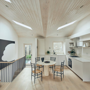 Exempel på ett mellanstort modernt beige beige kök, med släta luckor, vita skåp, rostfria vitvaror, ljust trägolv, beiget golv, en integrerad diskho, bänkskiva i terrazo, beige stänkskydd och stänkskydd i stenkakel