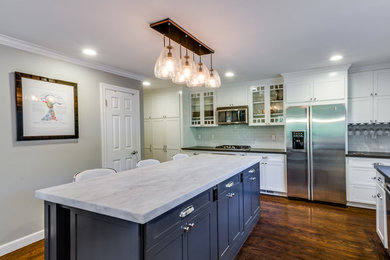 Inspiration for a mid-sized craftsman dark wood floor and brown floor eat-in kitchen remodel in San Francisco with shaker cabinets, white cabinets, marble countertops, white backsplash, glass tile backsplash, stainless steel appliances and an island