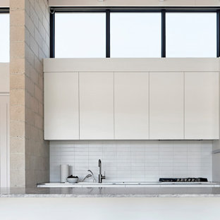 Photo of a contemporary galley kitchen in Melbourne with flat-panel cabinets, white cabinets, yellow splashback, with island, grey benchtop, exposed beam and wood.