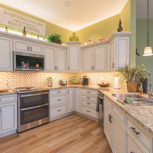 Photo of a small tropical u-shaped kitchen in Other with an undermount sink, white cabinets, granite benchtops, multi-coloured splashback, stone tile splashback, stainless steel appliances, porcelain floors, a peninsula, brown floor and recessed-panel cabinets.