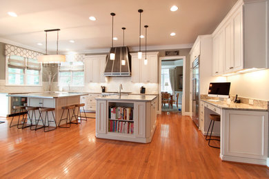 Kitchen - large transitional medium tone wood floor kitchen idea in DC Metro with an undermount sink, white cabinets, granite countertops, white backsplash, ceramic backsplash, stainless steel appliances and two islands