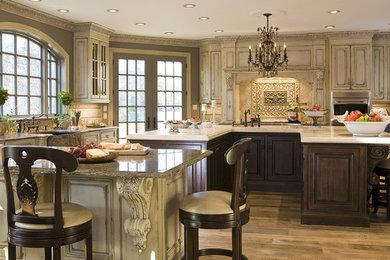 Inspiration for a large timeless u-shaped light wood floor and beige floor eat-in kitchen remodel in DC Metro with raised-panel cabinets, distressed cabinets, two islands, a farmhouse sink, granite countertops, beige backsplash, ceramic backsplash and stainless steel appliances