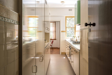 シドニーにある高級な小さなおしゃれなキッチン (シングルシンク、ステンレスカウンター、セラミックタイルのキッチンパネル、リノリウムの床、アイランドなし、茶色い床) の写真