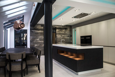 Large contemporary single-wall open plan kitchen in Other with an island, flat-panel cabinets, white cabinets, black appliances, porcelain flooring and an integrated sink.