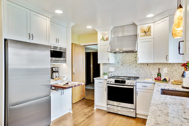 シアトルにある広いモダンスタイルのおしゃれな独立型キッチン (アンダーカウンターシンク、フラットパネル扉のキャビネット、白いキャビネット、グレーのキッチンパネル、シルバーの調理設備、淡色無垢フローリング、茶色い床、白いキッチンカウンター) の写真
