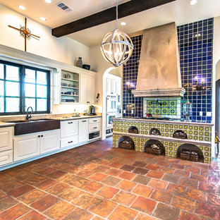 Photo of a mid-sized country galley eat-in kitchen in Austin with a farmhouse sink, limestone benchtops, blue splashback, terra-cotta splashback, terra-cotta floors and no island.