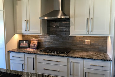 Inspiration for a mid-sized contemporary open concept kitchen remodel in Cedar Rapids with an undermount sink, gray backsplash, glass tile backsplash, stainless steel appliances, an island, shaker cabinets, white cabinets and granite countertops