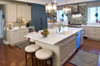 Example of a large classic u-shaped medium tone wood floor and brown floor open concept kitchen design in Newark with an undermount sink, recessed-panel cabinets, white cabinets, multicolored backsplash, stainless steel appliances, an island, solid surface countertops, wood backsplash and white countertops