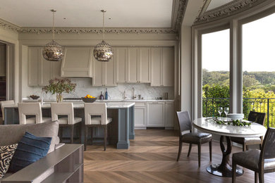 Example of a transitional galley medium tone wood floor open concept kitchen design in San Francisco with shaker cabinets, gray cabinets, white backsplash, stone slab backsplash and an island