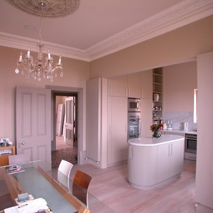 Design ideas for a small traditional u-shaped eat-in kitchen in London with an undermount sink, flat-panel cabinets, red cabinets, quartzite benchtops, white splashback, marble splashback, stainless steel appliances, light hardwood floors, with island and beige floor.