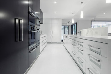 Photo of a large modern single-wall open plan kitchen in Canberra - Queanbeyan with flat-panel cabinets, black cabinets, marble worktops, an island, beige worktops, stainless steel appliances, ceramic flooring and white floors.