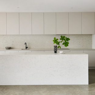 Design ideas for a mid-sized contemporary galley open plan kitchen with flat-panel cabinets, grey cabinets, quartz benchtops, white splashback, concrete floors, with island, grey floor, white benchtop, an undermount sink and stone slab splashback.