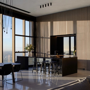 Contemporary galley open plan kitchen in Melbourne with beige splashback, with island, grey floor and black benchtop.