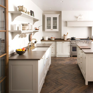 Ejemplo de cocina clásica, grande, cerrada, con armarios estilo shaker, puertas de armario blancas, electrodomésticos de acero inoxidable, suelo de madera oscura, una isla, suelo marrón, encimeras marrones y fregadero sobremueble