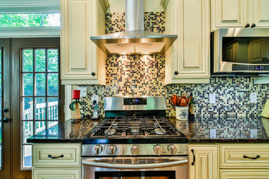 Large elegant u-shaped brown floor and light wood floor eat-in kitchen photo in Atlanta with an undermount sink, raised-panel cabinets, white cabinets, granite countertops, multicolored backsplash, stainless steel appliances, an island and mosaic tile backsplash