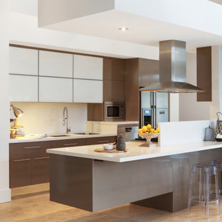 This is an example of a contemporary galley kitchen in Central Coast with an undermount sink, flat-panel cabinets, brown cabinets, stainless steel appliances, with island, beige floor and white benchtop.