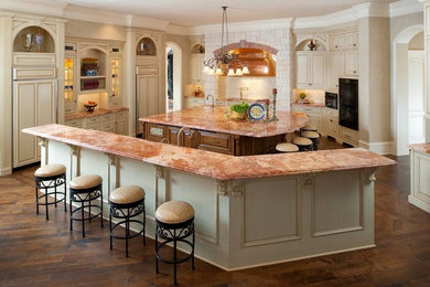 Kitchen - traditional brown floor kitchen idea in Dallas with raised-panel cabinets, beige cabinets, granite countertops, two islands and multicolored countertops