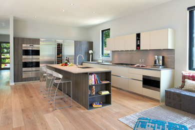 Foto de cocinas en L actual grande abierta con armarios con paneles lisos, electrodomésticos de acero inoxidable y una isla