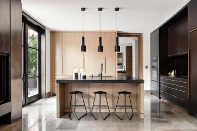Example of a trendy u-shaped beige floor kitchen design in Toronto with an undermount sink, flat-panel cabinets, dark wood cabinets, black appliances, an island and black countertops