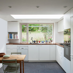 Design ideas for a mid-sized contemporary l-shaped eat-in kitchen in London with a double-bowl sink, flat-panel cabinets, white cabinets, wood benchtops, white splashback, stainless steel appliances, vinyl floors and grey floor.