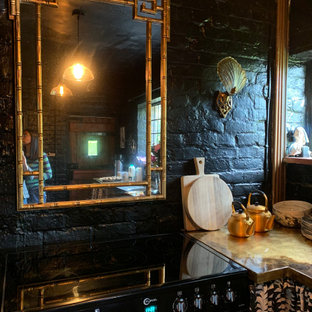Photo of a small arts and crafts u-shaped separate kitchen in Sussex with black splashback, black appliances, brick floors and red floor.
